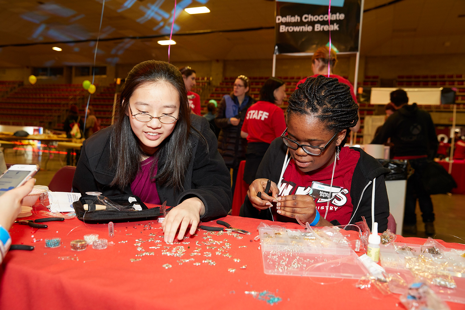 Two female MIT students sit at a table and work with small pieces of a puzzle