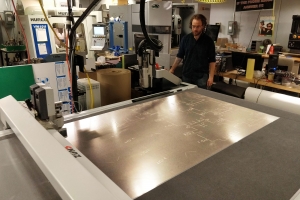 Graduate student Zach Fredin operates the Zund large-format cutter in MIT’s Center for Bit and Atoms. The machine was used to make prototypes of the face shield. Image: Center for Bits and Atoms