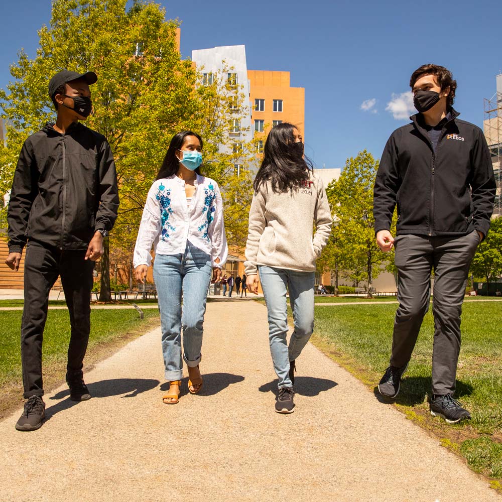 Image of four students walking on campus.