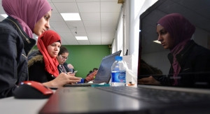Two students look at a laptop in the The MIT Refugee Action Hub (ReACT)