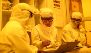 Canan Dagdeviren and two other reseachers, all wearing protective suits, work inside a YellowBox clean room.