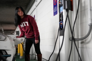 MIT student standing at an electric charging station fueling her vehicle